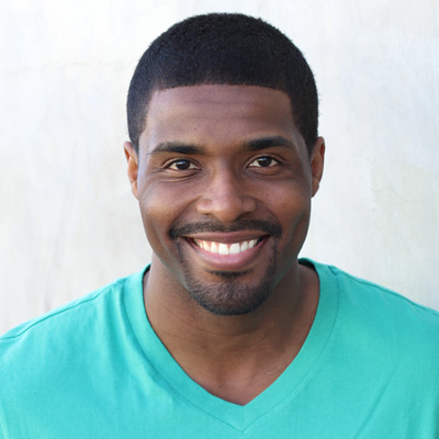 An older man and woman are seated closely together, smiling at the camera, with the man s arm around the woman, suggesting a loving relationship between them.