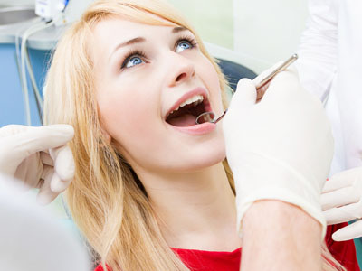 A woman receiving dental treatment, with a dentist working on her teeth, set against a medical background.